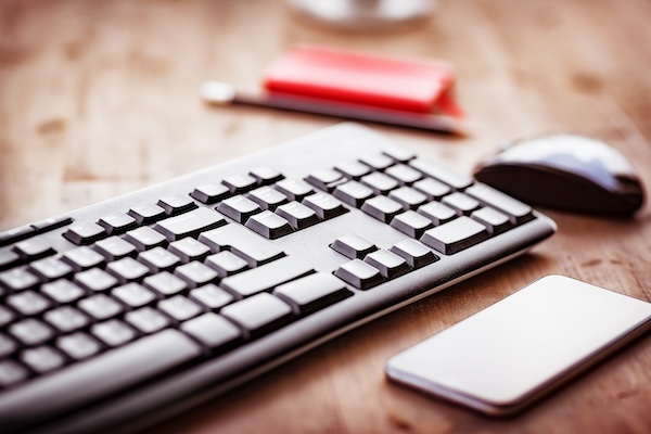 Desktop in the office, computer keyboard, pc mouse and mobile phone on the wooden table, work place